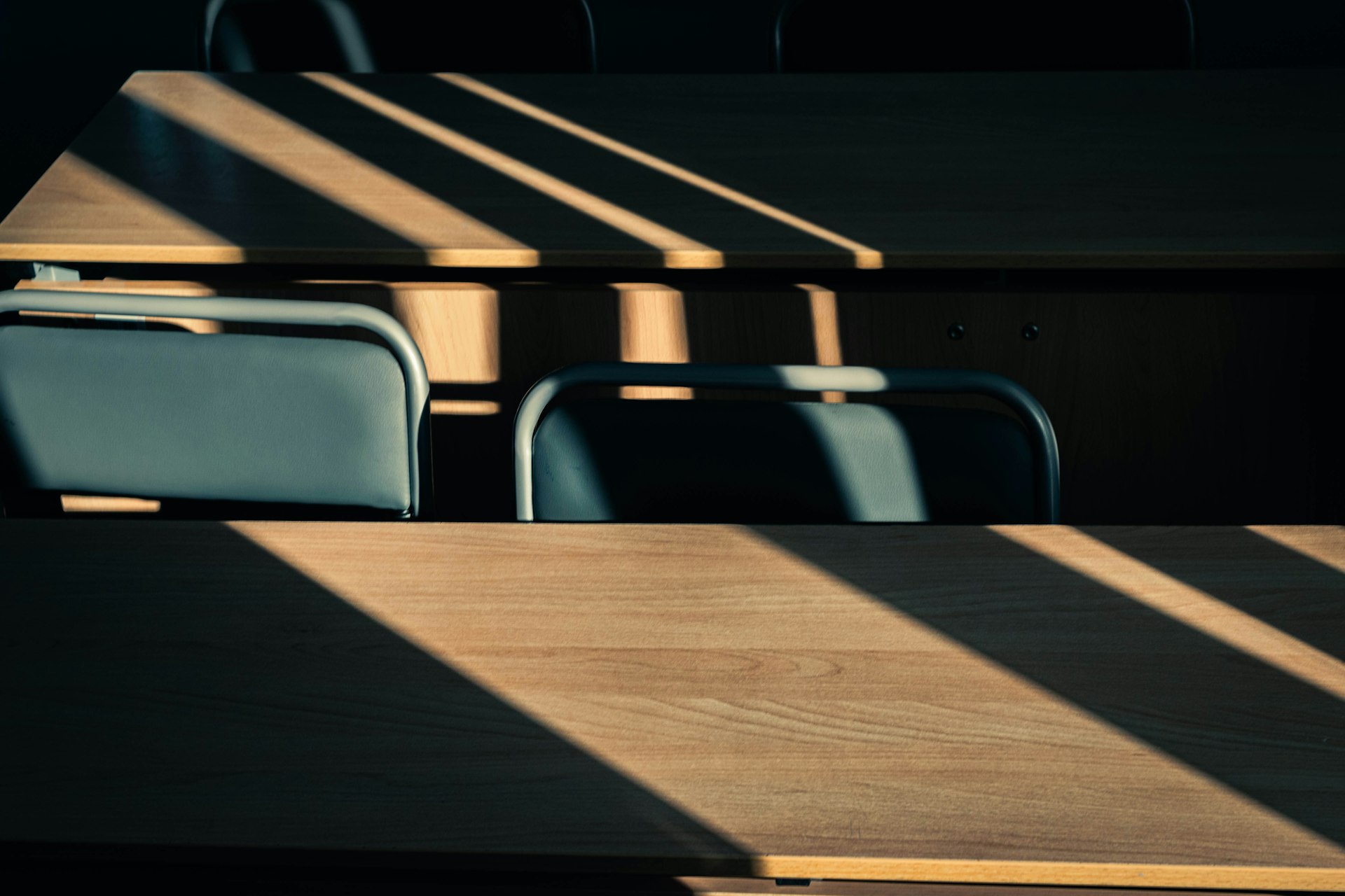Afternoon light falling across an empty classroom through wooden blinds