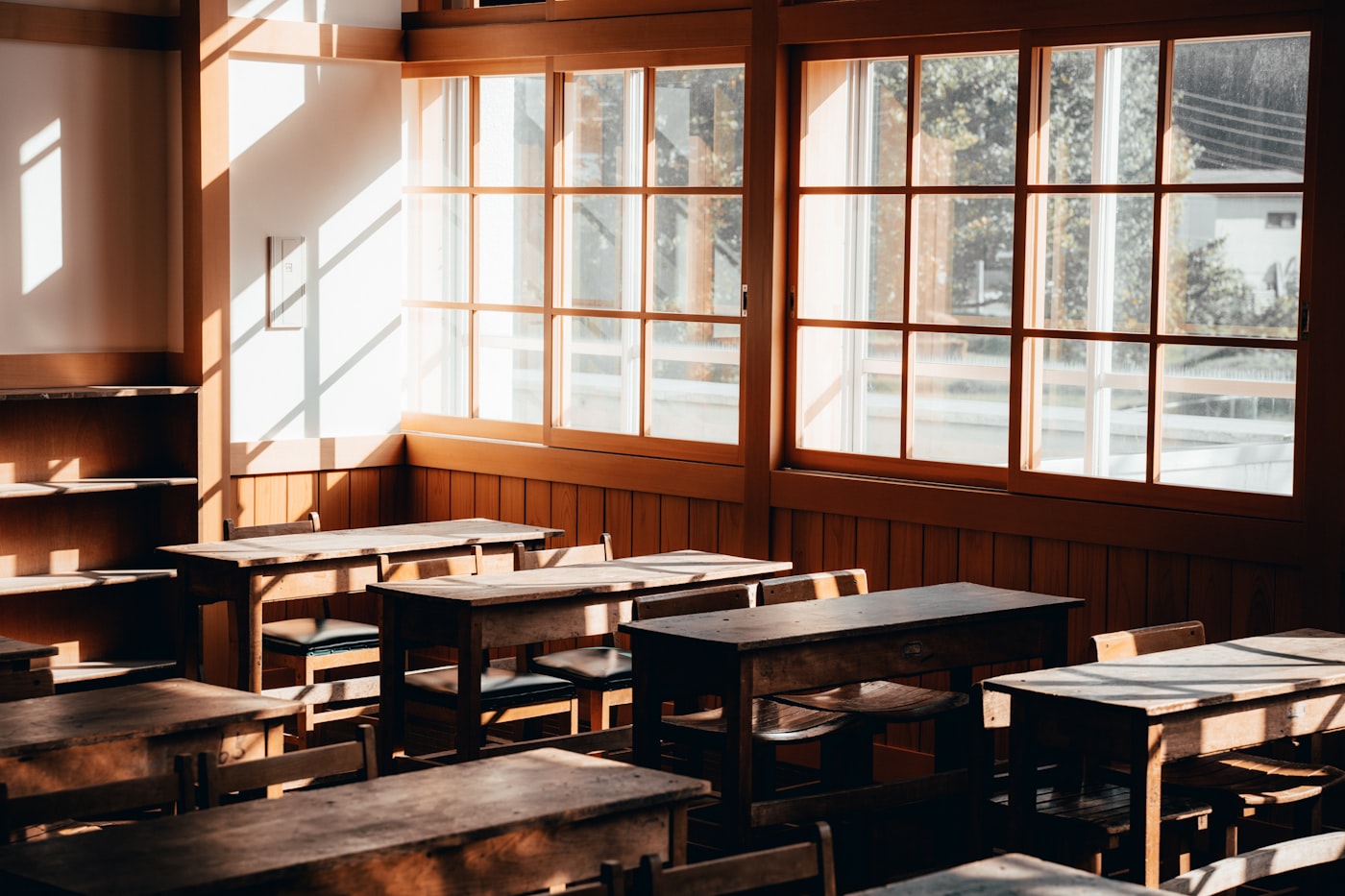 Empty modern classroom with wooden desks arranged in rows, afternoon light